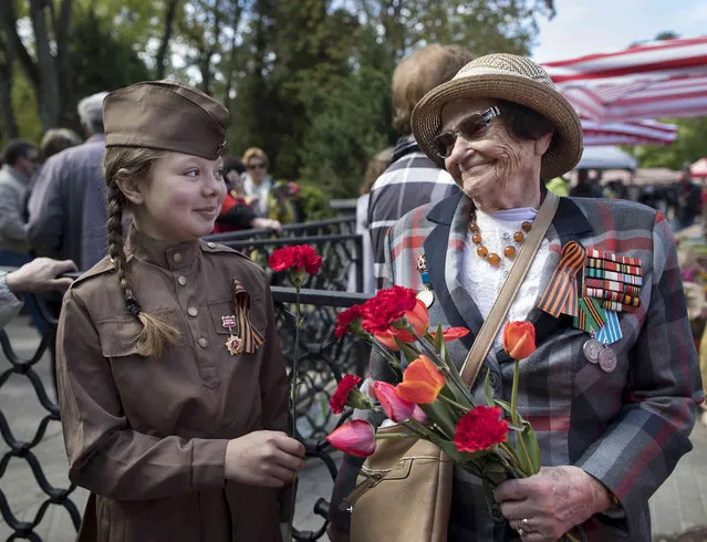 Tatijana Arhipova Efros, a 97 -year-old veteran of World War II, receives flowers at the Antakalnis memorial during Victory Day celebrations in Vilnius, Lithuania, Thursday, May 9, 2019. (Photo by Mindaugas Kulbis/AP Photo)