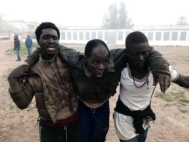 An immigrant receives help from his mates after they managed to jump over the fence at the border in Melilla, the Spanish enclave on the Northern African coast, March 18, 2014. A new massive assault to cross the border has led hundreds onto Spanish territory. Some have received medical attention as they arrived to the local temporary immigrant holding center (CETI) in Melilla after getting injured as they jumped the fence. (Photo by J. Rios/EPA)