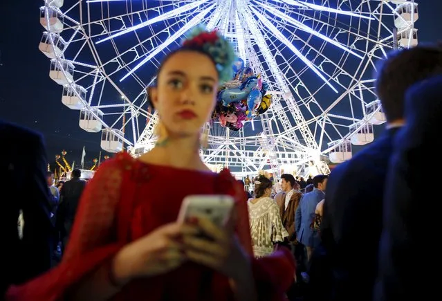 A woman wearing a sevillana dress holds a mobile phone during the traditional Feria de Abril (April fair) in the Andalusian capital of Seville, southern Spain, April 13, 2016. The fair will run until April 17. (Photo by Marcelo del Pozo/Reuters)