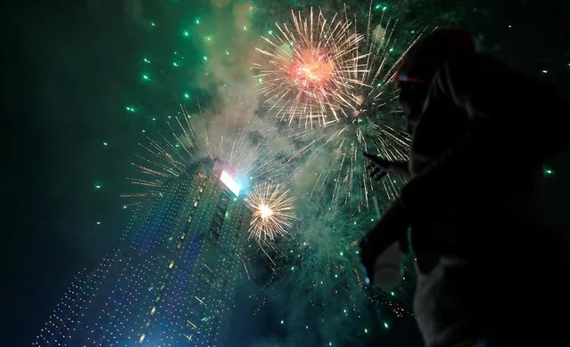 A reveller looks at fireworks explode over the UAP Old Mutual Tower during the New Year's Eve celebrations in Nairobi, Kenya on January 1, 2022. (Photo by Thomas Mukoya/Reuters)