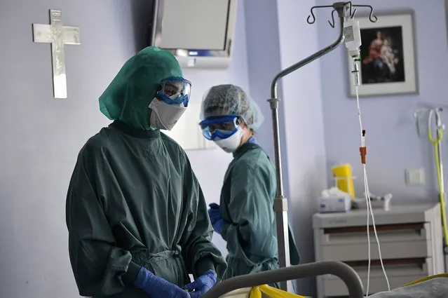 Members of the medical team attend to a patient with coronavirus, in the ICU department of the Clinica Universitaria, in Pamplona, northern Spain, Wednesday, January 12, 2022. Spain’s medical community has scored a victory after a court ordered that a regional government compensate doctors with up to 49,000 euros ($56,000) for having to work without personal protection suits during the devastating early months of the pandemic. (Photo by Alvaro Barrientos/AP Photo)