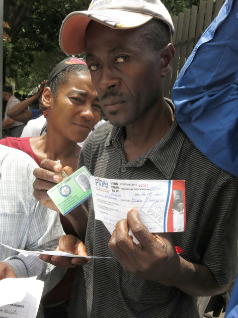 Delinua Dovil Jean Francois, right, shows the supporting documents that proves that he did the paperwork for obtaining his Haitian identity card, in order to apply for a temporary resident permit in the Dominican Republic, in Santo Domingo, Dominican Republic, Monday, June 15, 2015. Hundreds of Haitians are waiting in long lines throughout the Dominican Republic trying to secure legal residency as they face the threat of deportation. The government has given non-citizens until Tuesday to register under an initiative aimed at regulating the flow of migrants from neighboring Haiti. (AP Photo/Ezequiel Abiu Lopez)