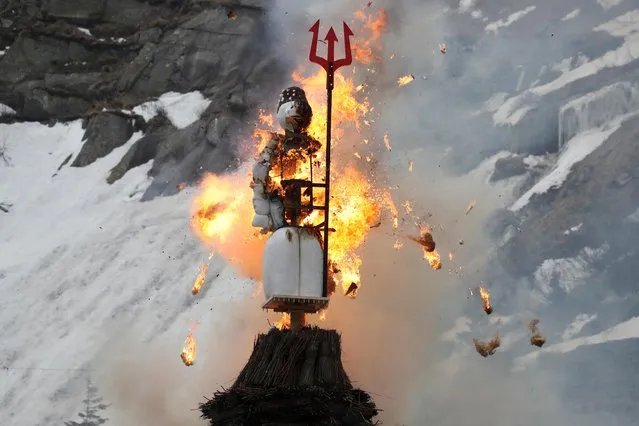 The Boeoegg, a snowman made of wadding and filled with firecrackers, is burning in a bonfire on the landmark of Devil's Bridge in the Schoellenen Gorge near the Alpine resort of Andermatt, Switzerland on April 19, 2021. (Photo by Arnd Wiegmann/Reuters)
