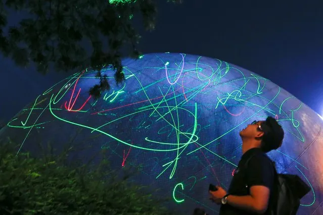 A man watches the dots of laser pointers move across the facade of the Hong Kong Space Museum during a flash mob staged to denounce the authorities' claim that laser pointers were offensive weapons in Hong Kong, China on August 7, 2019. Hundreds of Hong Kong protesters created their own light show to demonstrate against the arrest of a student detained for buying laser pointers, at the Space Museum in Tsim Sha Tsui. (Photo by Thomas Peter/Reuters)