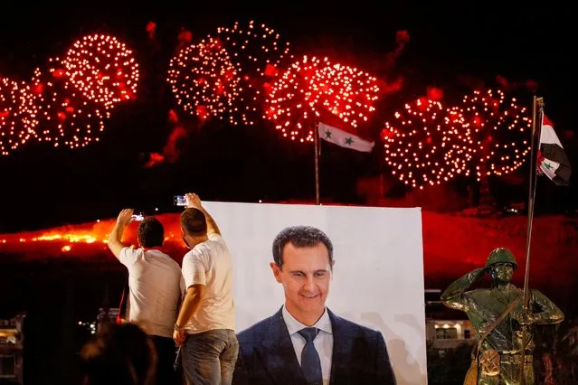 A poster depicting Syrian President Bashar al-Assad is seen as his supporters celebrate after the results of the presidential election announced that he won a fourth term in office, in Damascus, Syria, May 27, 2021. The win, dismissed by the opposition and the West as a farce, delivers Assad seven more years in power and lengthens his family's rule to nearly six decades. (Photo by Omar Sanadiki/Reuters)