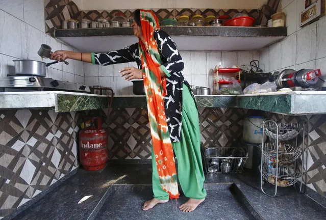 Geeta Nagar, a housewife, makes tea on a stove using a Liquefied Petroleum Gas (LPG) cylinder in her kitchen at Dujana village in Noida, on the outskirts of New Delhi October 7, 2015. (Photo by Anindito Mukherjee/Reuters)