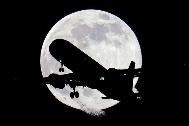 A plane flies past the moon in west London on Monday, January 17, 2022. The first full moon – the Wolf moon according to native north Americans – of 2022. (Photo by Victoria Jones/PA Images via Getty Images)