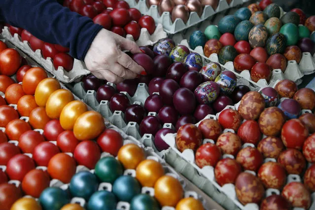 A buyer chooses hand decorated Easter eggs at a market in Belgrade, Serbia, Friday, April 14, 2017. Orthodox Serbs celebrate Easter on April 16, according to old Julian calendar. (Photo by Darko Vojinovic/AP Photo)
