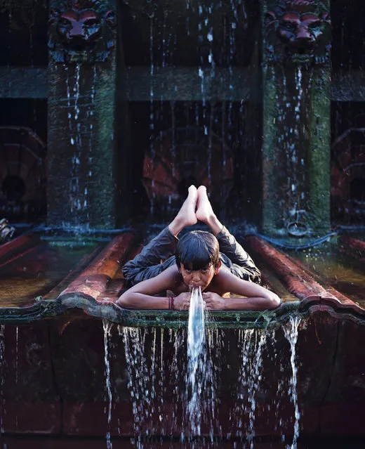 Golu, a ten-year-old boy living on the streets of India's capital New Delhi, lays on cascading water as he plays in a fountain in a decorative shallow pool adorning the gardens surrounding the India Gate monument on a hot Indian summer afternoon in New Delhi on May 20, 2016. The Indian Meterological Department issued warnings of “severe heat wave” conditions across large parts of India's north and west, including the capital Delhi, where temperatures hit 47 degrees Celsius earlier this week. (Photo by Roberto Schmidt/AFP Photo)