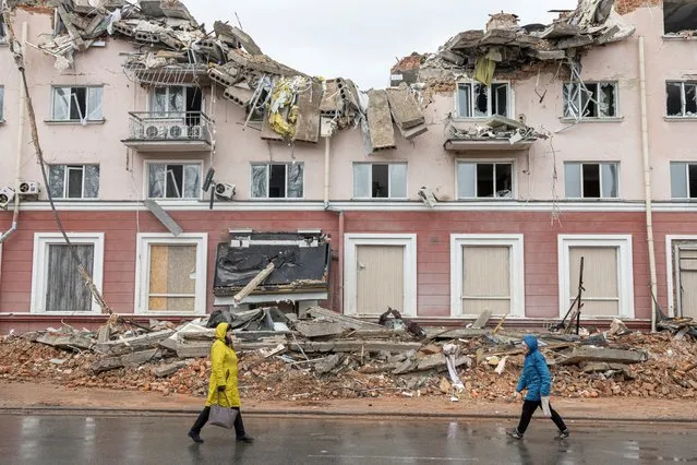 Women walk along a street in front of the destroyed Hotel Ukraine, as Russia's invasion of Ukraine continues, in Chernihiv, Ukraine, April 6, 2022. (Photo by Marko Djurica/Reuters)
