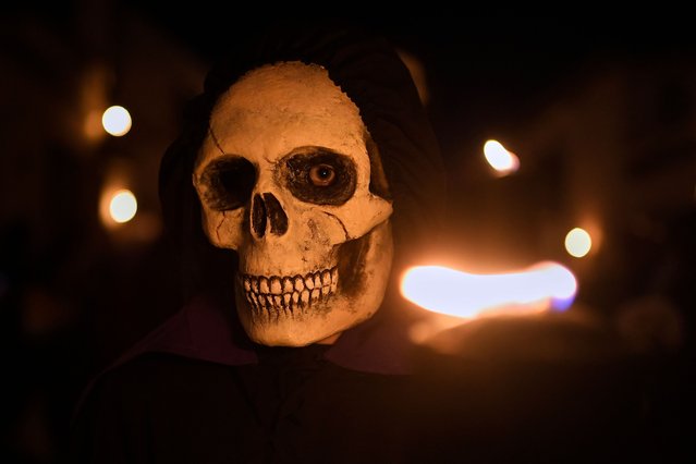 Penitents wearing skull masks take part in the Maundy Thursday procession in Verges, northeastern Spain, on April 6, 2023. Spain's colourful Holy Week celebrations began on April 2 -Palm Sunday-, featuring centuries-old processions of the faithful carrying flower-covered floats topped with statues of Christ or the Virgin Mary that draw huge crowds. Organised by various religious brotherhoods, or “confradias”, the parades are held across the country in the week leading up to Easter Sunday, which this year in the Roman Catholic Church falls on April 9. (Photo by Pau Barrena/AFP Photo)