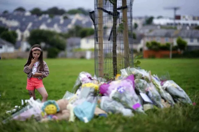 A young girl blows a kiss as she looks at floral tributes at the scene of a shooting in the Keyham area of Plymouth, England, Saturday, August 14, 2021. Britain’s police watchdog says it has launched an investigation into why a 22-year-old man who fatally shot five people in southwestern England was given back his confiscated gun and gun license. Police have said Jake Davison killed his mother and four other people, including a 3-year-old girl, before taking his own life in Plymouth. (Photo by Ben Birchall/PA Wire via AP Photo)