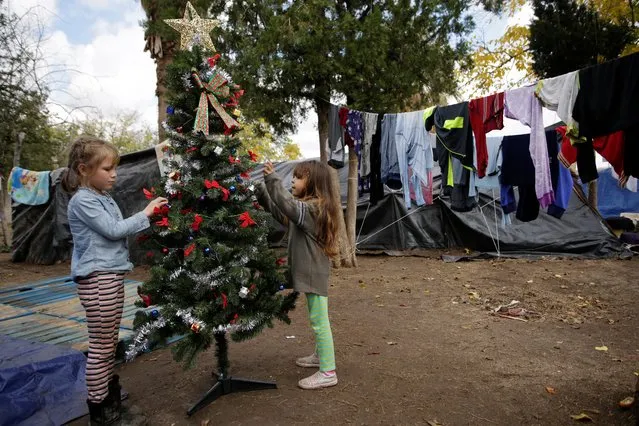 Mexican children, who along with their parents are fleeing from violence in their hometown and are currently camping near the Cordova-Americas international border crossing bridge while waiting to apply for asylum to the U.S., arrange a Christmas tree, in Ciudad Juarez, Mexico on December 10, 2019. (Photo by Jose Luis Gonzalez/Reuters)