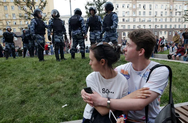 A couple sits in front of riot police standing guard during an anti-corruption protest organised by opposition leader Alexei Navalny, on Tverskaya Street in central Moscow, Russia on Monday, June 12, 2017. (Photo by Maxim Shemetov/Reuters)