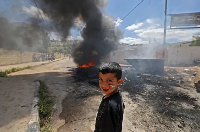 A Palestinian child stands in front of burning tyres in the refugee camp of Jenin in the occupied West Bank after an Israeli military raid on April 12, 2022. Israeli troops launched a fourth day of operations around Jenin after an assailant from the district shot and killed three people and wounded 12 in a Tel Aviv bar last week in an attack that stunned the country. (Photo by Jaafar Ashtiyeh/AFP Photo)