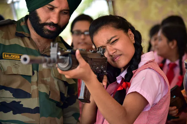 An Indian army soldier looks on while a student aims with a assault rifle during a “Know Your Army” exhibition at Government Dungar Collage in Bikaner, in the Indian state of Rajasthan on August 20, 2019. (Photo by Dinesh Gupta/AFP Photo)