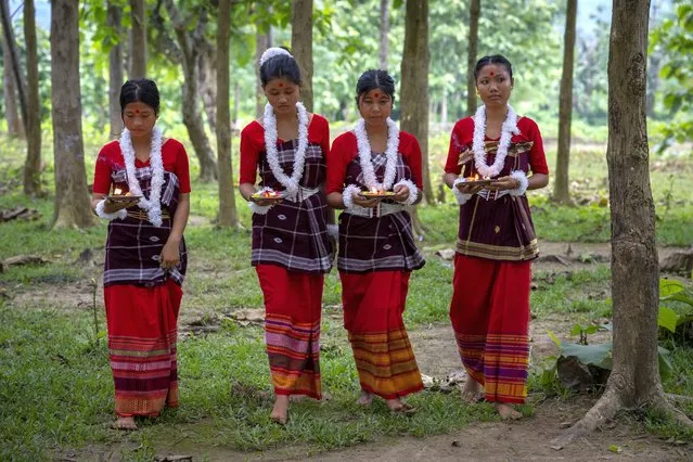 Indian Rabha tribal girls in traditional attire bring offerings before they perform a tribal Rabha dance during Baikho festival at Gamerimura village along the Assam Meghalaya border, west of Gauhati, India, Saturday, June 4, 2022. (Photo by Anupam Nath/AP Photo)