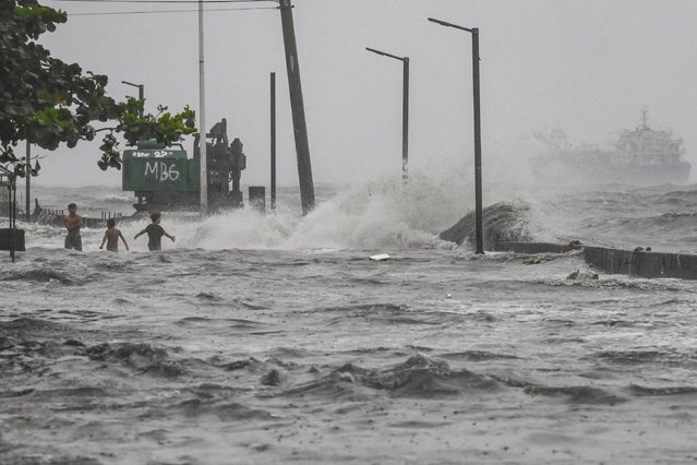 Youths wade in a storm surge along Manila Bay amid heavy rains brought by Tropical Storm Yagi in Manila on September 2, 2024. A tropical storm dumped heavy rain in the Philippines for a second day on September 2, causing floods and landslides that have left at least four people dead, including a nine-month-old girl, officials said. (Photo by Jam Sta Rosa/AFP Photo)