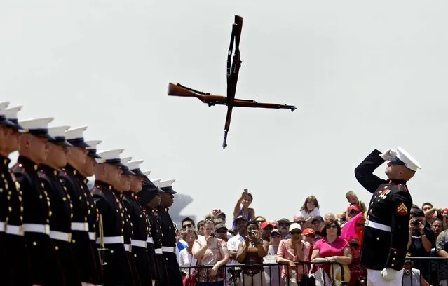 Two rifles are thrown through the air as the Marine silent drill platoon performs at Burke Lakefront Airport in Cleveland, during Marine Week festivities in the city on June 16, 2012