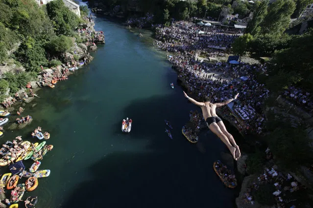 A diver drops through the air from the Mostar bridge during the 451th traditional annual high diving competition, in Mostar, 140 kms south of Bosnian capital of Sarajevo, Sunday, July 30, 2017. Total of 41 divers from Bosnia and neighbouring countries competed diving from 25 meters high Old Mostar Bridge into the Neretva river. (Photo by Amel Emric/AP Photo)