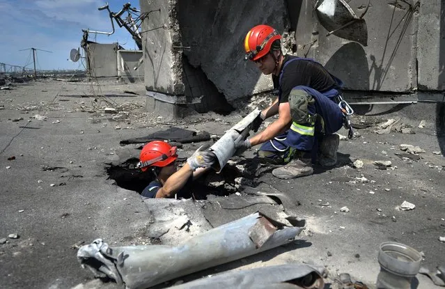 Ukrainian rescuers search for and retrieve the remains of Russian shells on the roof of a high-rise building damaged by Russian shelling in one of the residential areas of Kharkiv, Ukraine, Thursday, June 30, 2022. (Photo by Sofiia Bobok/AP Photo)