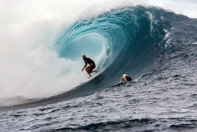 A cameraman floats in the water filming USA's Kelly Slater as he competes in the 2015 Billabong Pro Tahiti, World Surf league tour no.7, along the Teaupoo coast, western Tahiti on August 15, 2015. Australia's Mick Fanning made his first appearance in this competition since being attacked on July 19 by a shark in the Final of the J-Bay Open, off the coast of South Africa. (Photo by Gregory Boissy/AFP Photo)