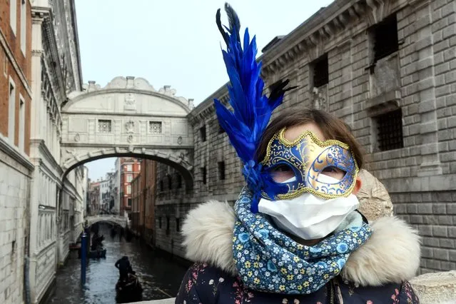 A young tourist wearing a protective facemask and a Carnival mask visits the streets of Venice, on February 24, 2020 during the usual period of the Carnival festivities which the last two days have been cancelled due to an outbreak of the COVID-19 the novel coronavirus, in northern Italy. Italy reported on February 24, 2020 its fourth death from the new coronavirus, an 84-year old man in the northern Lombardy region, as the number of people contracting the virus continued to mount. (Photo by Andrea Pattaro/AFP Photo)