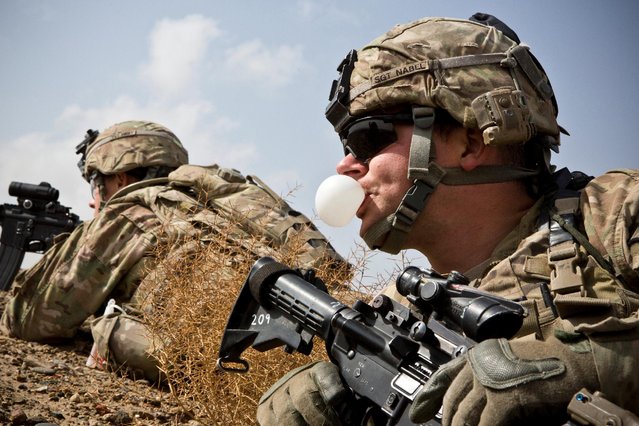 A U.S. Army soldier with Charlie Company, 36th Infantry Regiment, 1st Armored Division blows a bubble with his chewing gum during a mission near Command Outpost Pa'in Kalay in Maiwand District, Kandahar Province February 3, 2013. (Photo by Andrew Burton/Reuters)