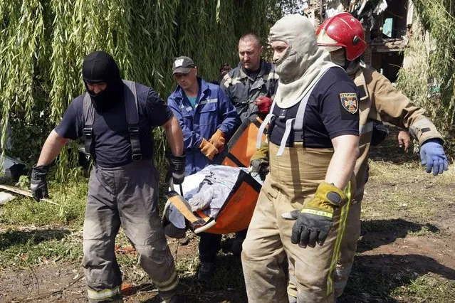 Rescuers move a covered body of a woman killed by Russian missile attack on Monday in Chuhuiv, Kharkiv region, Ukraine, Tuesday, July 26, 2022. (Photo by Andrii Marienko/AP Photo)