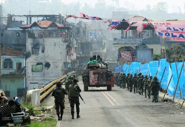 An Armoured Personnel Carrier (APC) and government troops march towards Mapandi bridge after 100 days of intense fighting between soldiers and insurgents from the Maute group, who have taken over parts of Marawi city, southern Philippines August 30, 2017. (Photo by Froilan Gallardo/Reuters)
