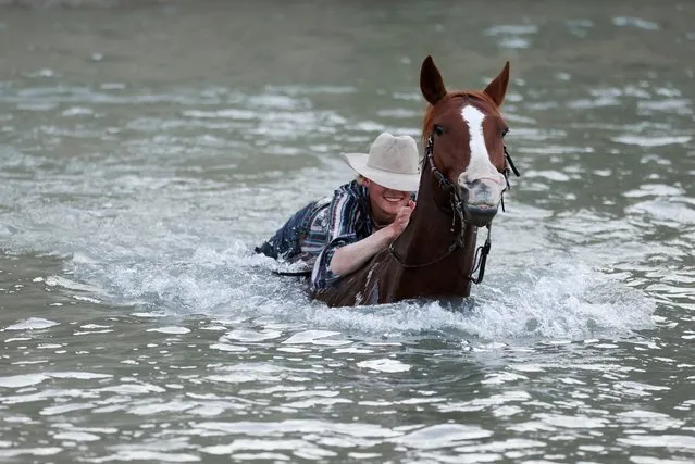 After competing in the Writing-On-Stone Rodeo, Ryder Nelson cools off in the Milk River during the first Writing-On-Stone Rodeo held since the coronavirus disease (COVID-19) pandemic in the World Heritage Site location of Writing-On-Stone Provincial Park, Alberta, Canada on July 31, 2022. (Photo by Leah Hennel/Reuters)