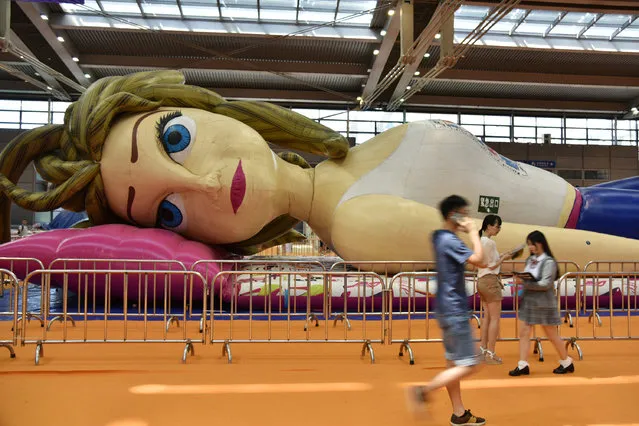 People walk past a giant inflatable doll presented during Comic-Con in Shenzhen, Guangdong Province, China, July 23, 2016. (Photo by Reuters/Stringer)