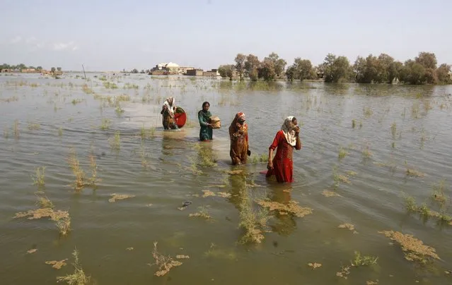 Pakistani women wade through floodwaters as they take refuge in Shikarpur district of Sindh Province, of Pakistan, Friday, September 2, 2022. Pakistani health officials on Thursday reported an outbreak of waterborne diseases in areas hit by recent record-breaking flooding, as authorities stepped up efforts to ensure the provision of clean drinking water to hundreds of thousands of people who lost their homes in the disaster. (Photo by Fareed Khan/AP Photo)