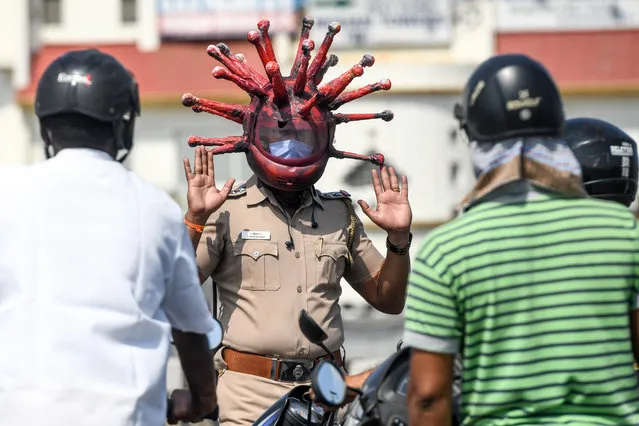 Police inspector Rajesh Babu (C) wearing a coronavirus-themed helmet speaks to motorists at a checkpoint during a government-imposed nationwide lockdown as a preventive measure against the COVID-19 coronavirus in Chennai on March 28, 2020. (Photo by Arun Sankar/AFP Photo)