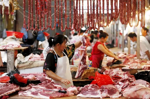 A vendor checks on her pork meat at a market in Hangzhou, Zhejiang province, August 9, 2015. (Photo by Reuters/Stringer)