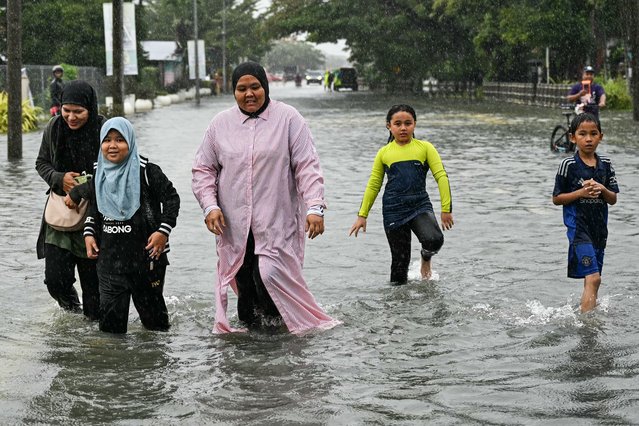 Residents wade through flood waters on a street as it rains in Pasir Puteh in Malaysia's Kelantan state on November 30, 2024. More than 122,000 people have been forced out of their homes as massive floods caused by relentless rains swept through Malaysia's northern states, disaster officials said November 30. (Photo by Mohd Rasfan/AFP Photo)