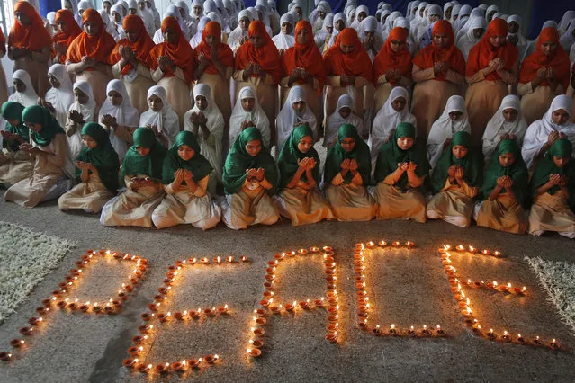 Indian students lined up in the color of the Indian flag pray for peace at a function remembering victims of atomic bombs dropped on Japanese cities of Hiroshima and Nagasaki at a school in Ahmadabad, India, Tuesday, August 9, 2016. On August 9, 1945, three days after the atomic bombing of Hiroshima, the U.S. dropped another bomb over Nagasaki, killing an estimated 74,000 people. (Photo by Ajit Solanki/AP Photo)