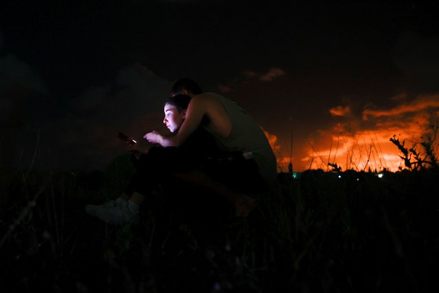 People use a phone on the ground, on the day Iran fired a salvo of ballistic missiles at Israel, near Tel Aviv, Israel, on October 1, 2024. (Photo by Ammar Awad/Reuters)