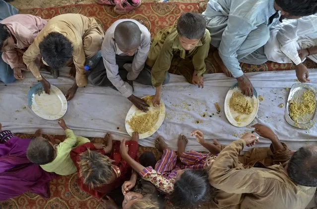 Children eat food provided by a charity group, in Jaffarabad, a flood-hit district of Baluchistan province, Pakistan, Thursday, September 15, 2022. The devastating floods affected over 33 million people and displaced over half a million people who are still living in tents and make-shift homes. The water has destroyed 70% of wheat, cotton and other crops in Pakistan. (Photo by Zahid Hussain/AP Photo)