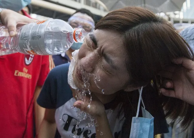 A pro-democracy protester has pepper spray washed from her eyes by sympathetic supporters as they block the main highway through Admiralty, next to the Hong Kong government's headquarters in Hong Kong's downtown district, on the first day of the mass civil disobedience campaign Occupy Central, Hong Kong, China, 28 September 2014. (Photo by Alex Hofford/EPA)