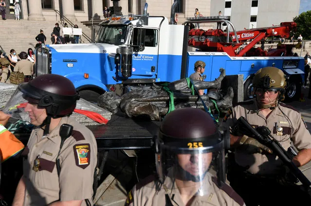 State Patrol officers stand guard as employees of Twin Cities Transport and Recovery work to clear the toppled statue of Christopher Columbus on the Minnesota State Capitol Grounds in St Paul, Minnesota, U.S. June 10, 2020. (Photo by Nicholas Pfosi/Reuters)