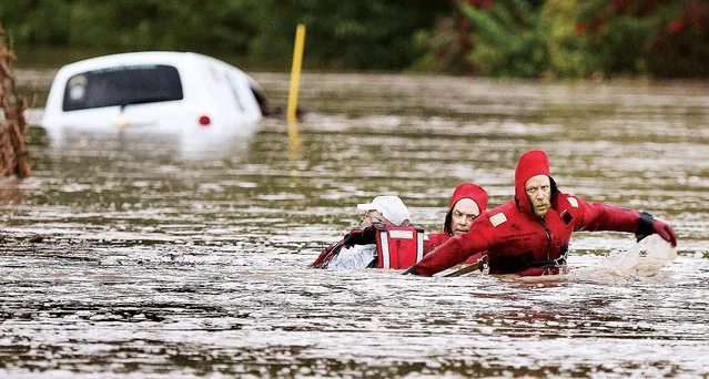 Alton, Ill., Fire Department Batallion Chief Brad Sweetman, right, and Alton Capt. Matt Fischer, center, help pull an unidentified man to safety Thursday morning, October 2, 2014, after the man's vehicle was overcome by a flash flood in Jersey County, near Alton, Ill. The man, who had been trapped with his vehicle since about 4 a.m., was exhausted from the ordeal but uninjured.  (Photo by John Badman/AP Photo/The Telegraph)