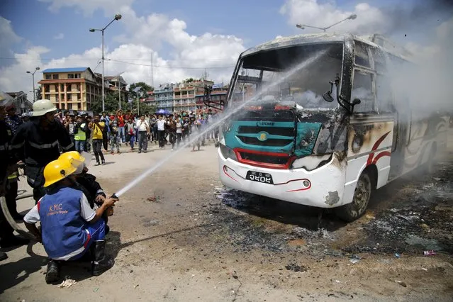 Firefighters try to douse fire set by unidentified protesters on a passenger bus during the nationwide strike, called by the opposition parties against the proposed constitution, in Kathmandu, Nepal September 20, 2015. (Photo by Navesh Chitrakar/Reuters)