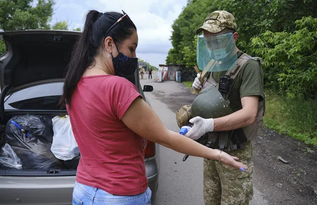 An Ukrainian soldier checks the temperature of a woman as she crosses the Novotroitske checkpoint between the Ukrainian government and pro-Russian militants controlled territories not far from Donetsk, Ukraine, 22 June 2020. Ukraine and self-proclaimed Donetsk People's Republic reopened Novotroitske checkpoint amid quarantine relaxation in the ongoing coronavirus COVID-19 pandemic. (Photo by Yevgen Honcharenko/EPA/EFE)