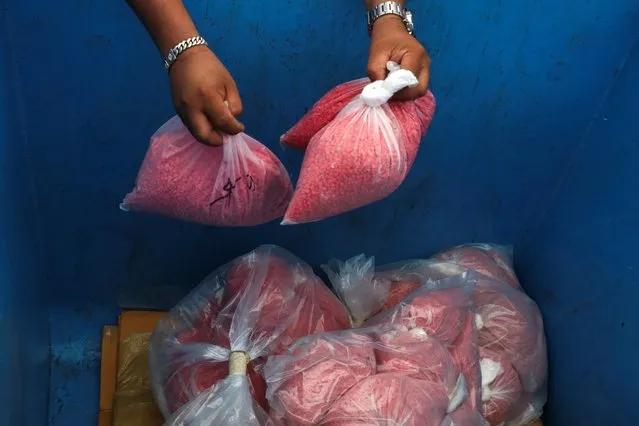 Thai narcotics officials put bags of methamphetamine pills into a bin during the 50th Destruction of Confiscated Narcotics ceremony in Ayutthaya province, Thailand, June 26, 2020. (Photo by Athit Perawongmetha/Reuters)