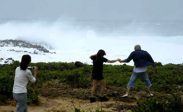 People visit a cape to watch rough sea in Yomitan Village, Japan's southern island of Okinawa Sunday, October 12, 2014. A powerful typhoon poured heavy rains over Okinawa and was aiming at the next island of Kyushu on Sunday, becoming the second severe storm to hit in a week. (Photo by AP Photo/Kyodo News)