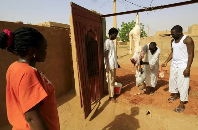 Men hang a slaughtered sheep at the door of a house after performing Eid al-Adha prayers in Khartoum, Sudan September 24, 2015. (Photo by Mohamed Nureldin Abdallah/Reuters)