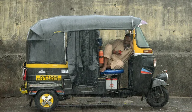 An Indian auto-rickshaw driver checks his mobile as he takes a break during rain showers in Mumbai on December 5, 2017. Cyclone Ockhi brought heavy rain to Mumbai as it moved up the Indian west coast, after hitting southern India and Sri Lanka, killing at least 26 people and cutting power to millions. (Photo by Punit Paranjpe/AFP Photo)