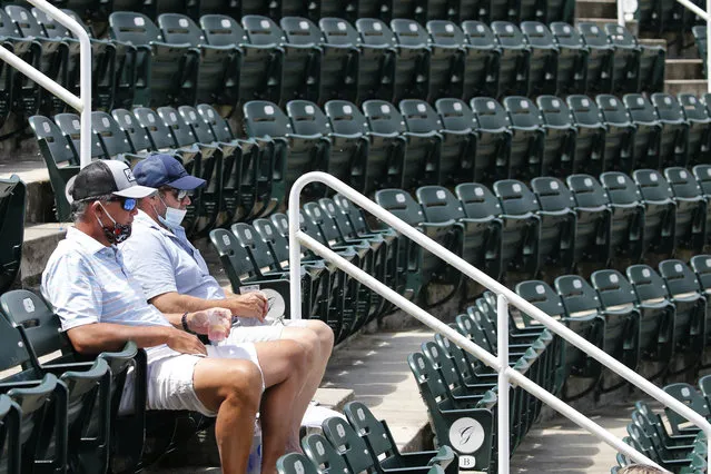 Tennis fans, Jeff Hartman, left, and Clay Gilbert, right, watch play at the start of the World Teamtennis tournament at an empty tennis arena at The Greenbrier Resort Sunday July 12, 2020, in White Sulphur Springs, W.Va. (Photo by Steve Helber/AP Photo)