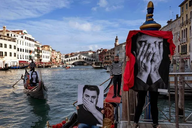 Gondoliers show black and white pictures of models covering their eyes, ears or mouths, in a direct representation of the three stages of silence: “I don't see, I don't hear, I don't speak”, during a flash mob to mark the International Day of Violence against Women, on Venice's Grand Canal, near the Rialto Bridge, on November 25, 2022. The Walls of Silence project by Mjriam Bon and Giusy Versace lands in Venice on November 25, 2022, where it makes as a flash mob with ten gondolas parade along the Grand Canal, with black and white images which invite us to reflect on the curtain of silence that too often envelops countless stories of violence, abuse and daily abuse. (Photo by Andrea Pattaro/AFP Photo)
